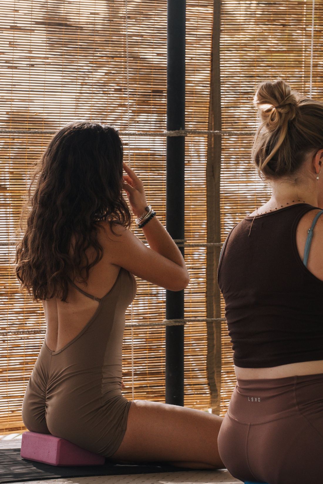 Seated breathwork in front of golden bamboo shutters